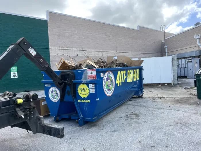 Contenedor de Javi's cargado con gabinetes y escombros de remodelación detrás de un edificio comercial