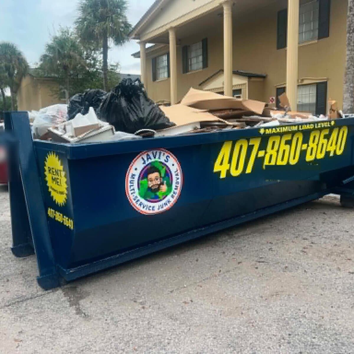 Javi's navy 15 yard dumpster loaded with cardboard, bags and remodel debris, the maximum load level marked on the side