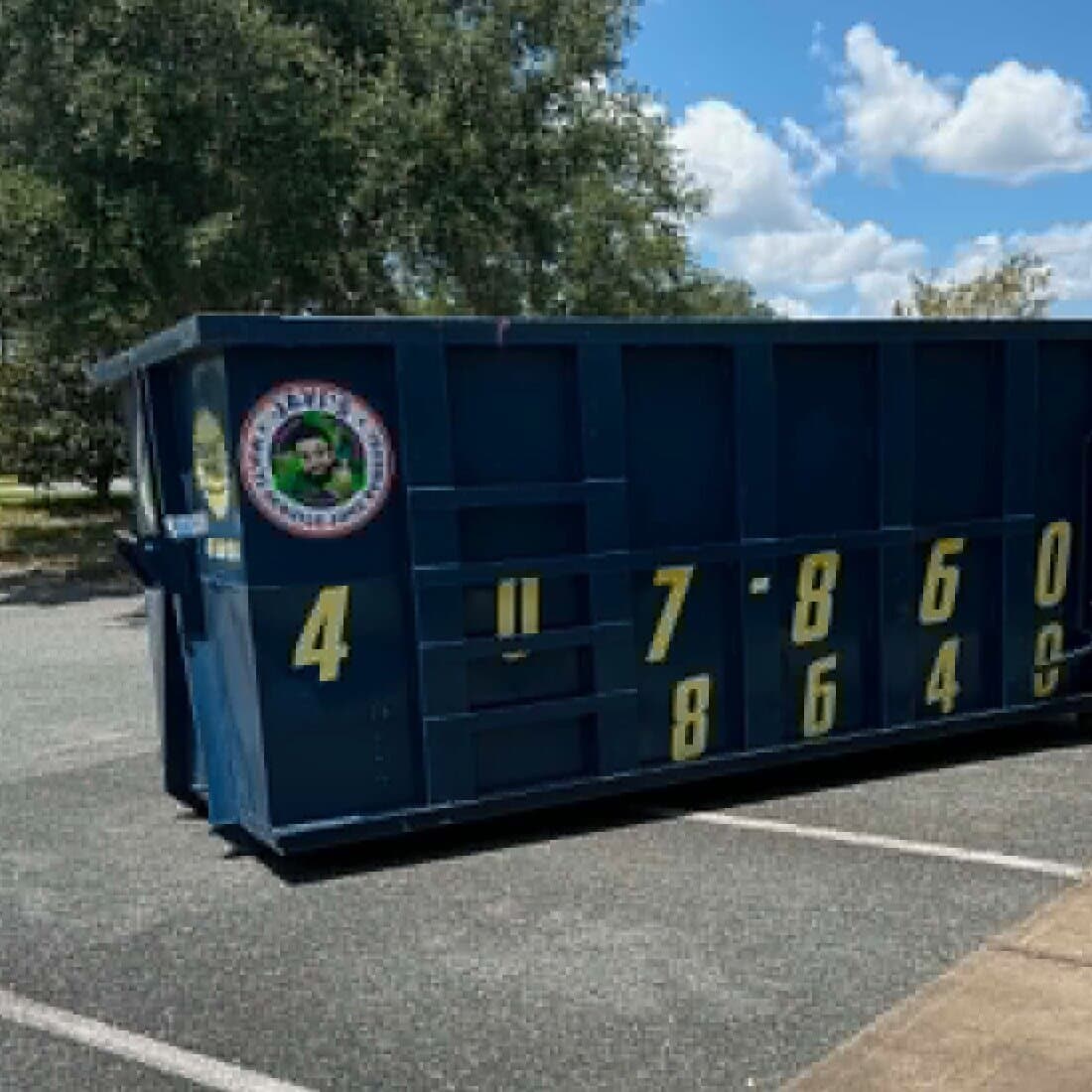Javi's 30 yard dumpster set across parking spaces in an open lot, phone number lettered on the side